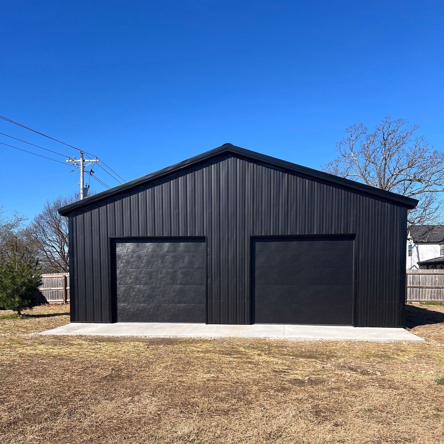 All black detached 30x30 garage in gravette arkansas with two garage doors.