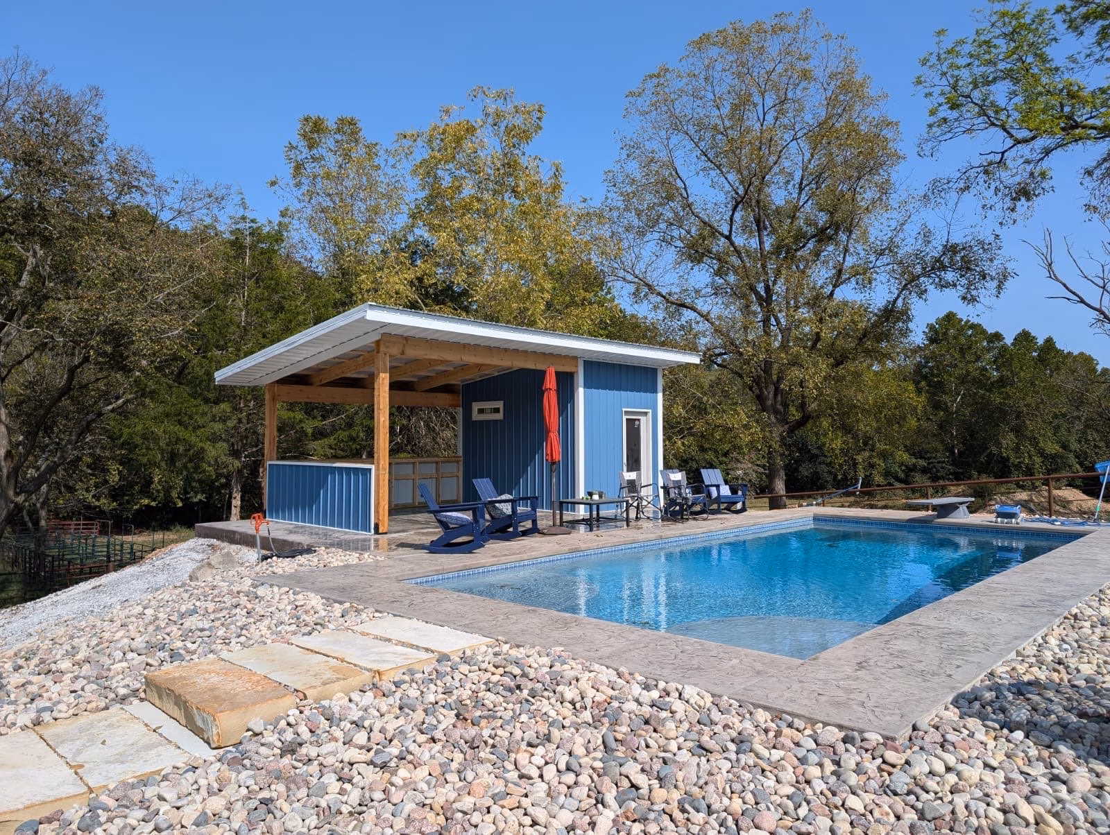 blue pool house cabana beside a pool in Arkansas. Built by Yutzy Construction