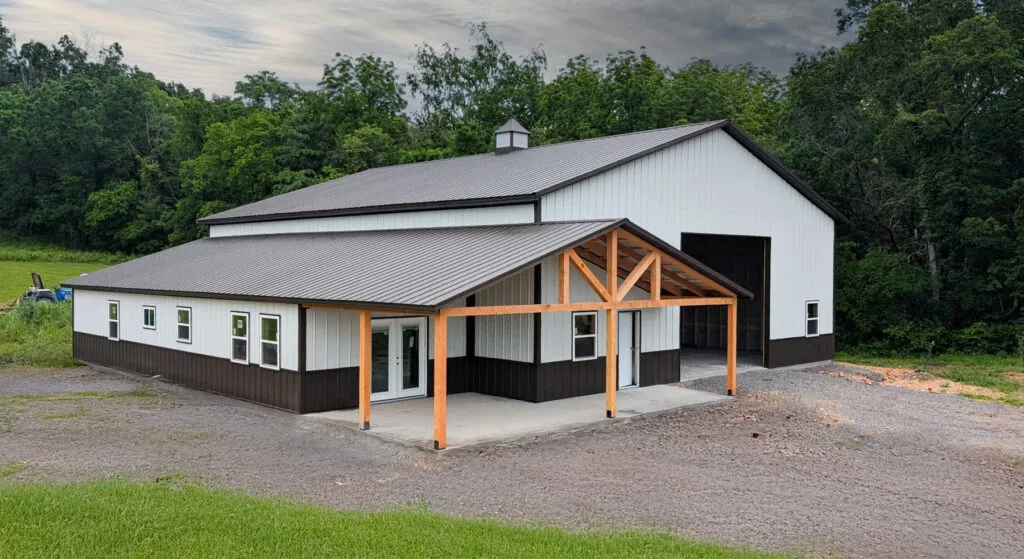 a barndominium building in northwest arkansas with white metal siding and a dark metal roof.